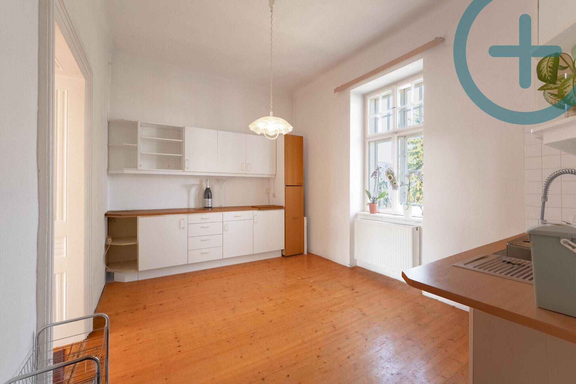 Helle Küche mit weißen Einbauschränken, Holzarbeitsplatte und großem Fenster.