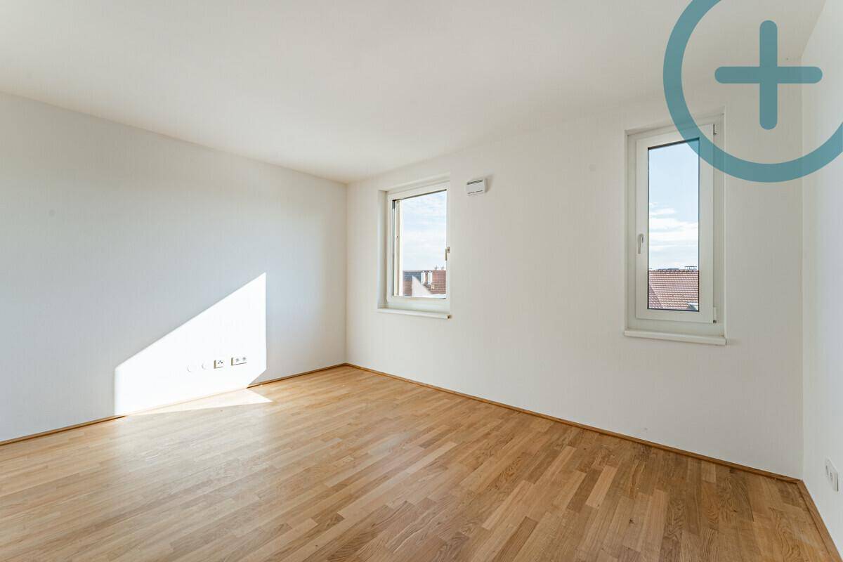 Geräumiges Zimmer mit Parkettboden und viel Tageslicht durch die Fenster, ideal für Wohnzwecke.