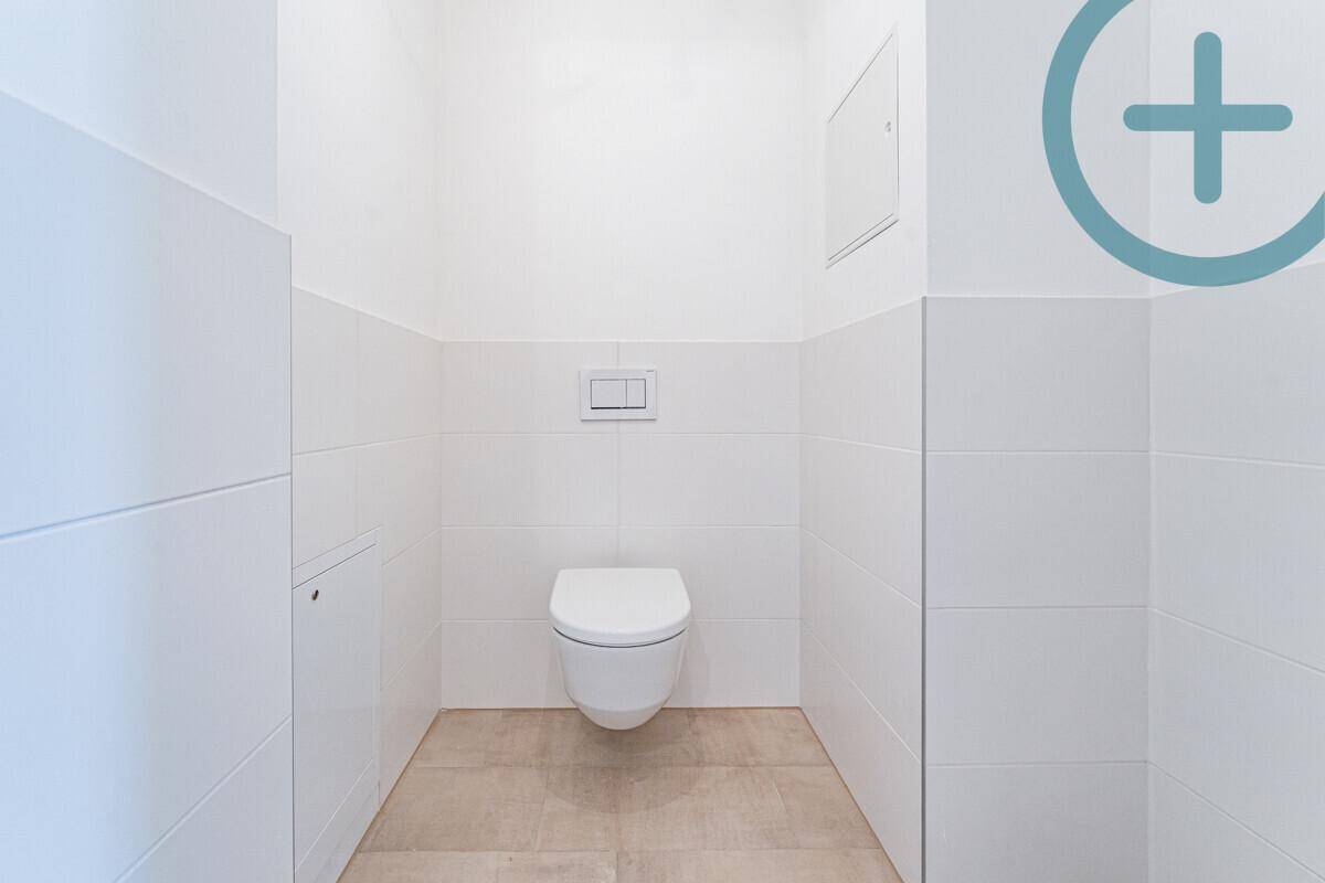 Modernes Gäste-WC mit wandhängender Toilette und hellen Fliesen an den Wänden.