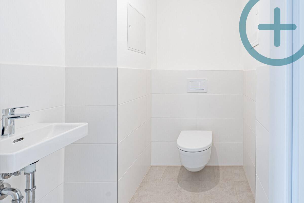 Modernes Gäste-WC mit weißen Fliesen, wandhängendem WC und kleinem Waschbecken.