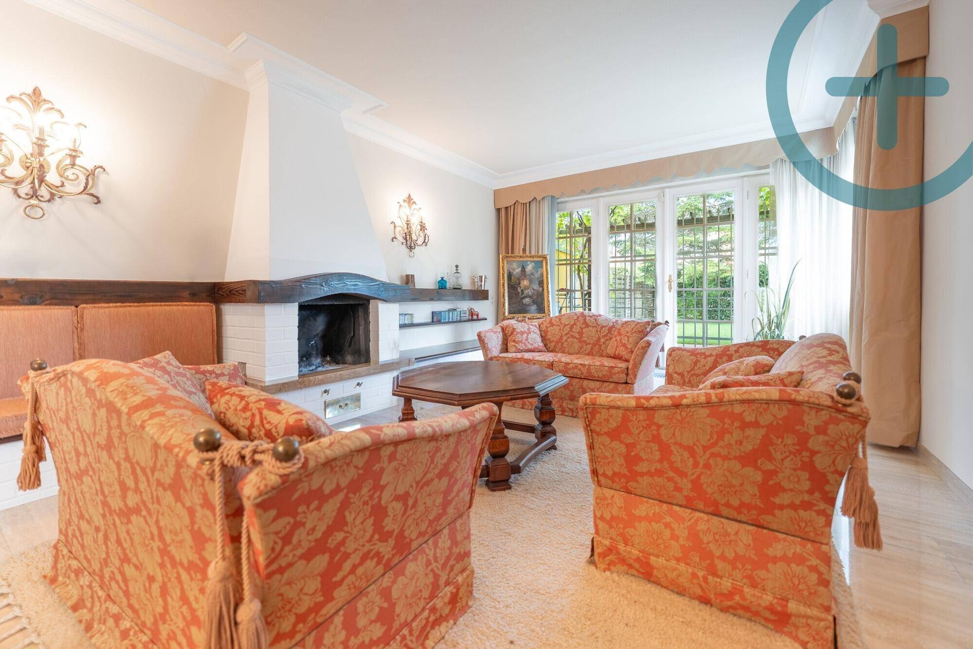 Gemütliches Wohnzimmer mit Kamin, bequemen Sofas und Blick in den Garten.