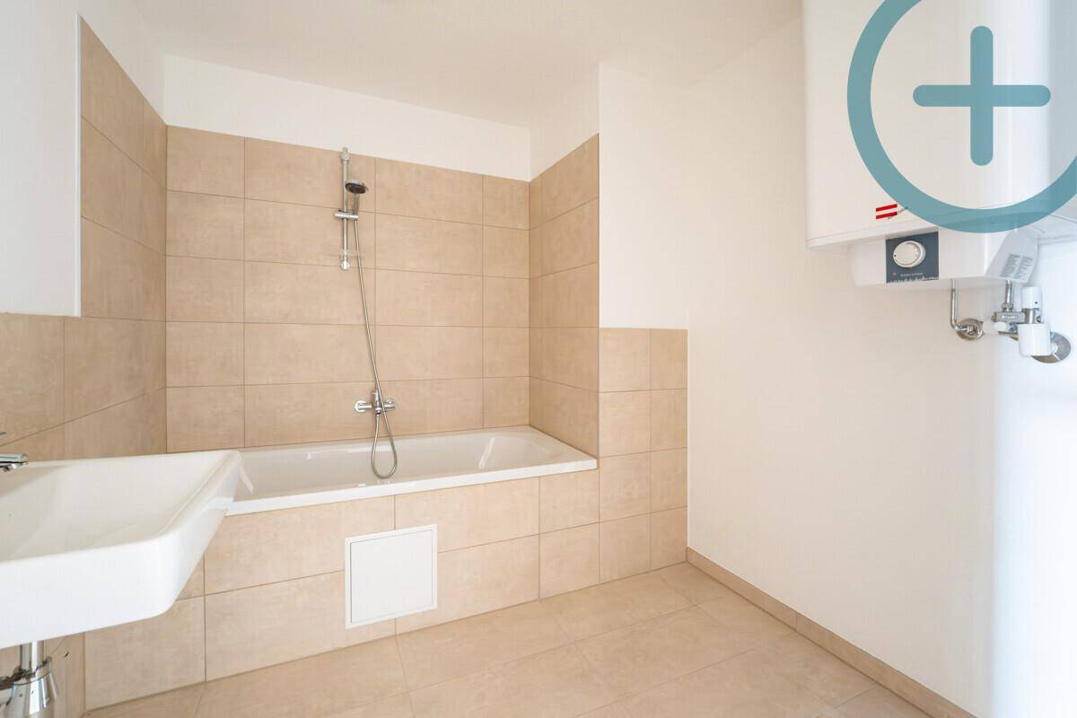 Funktionales Badezimmer mit beigefarbenen Fliesen, Badewanne und Waschbecken.