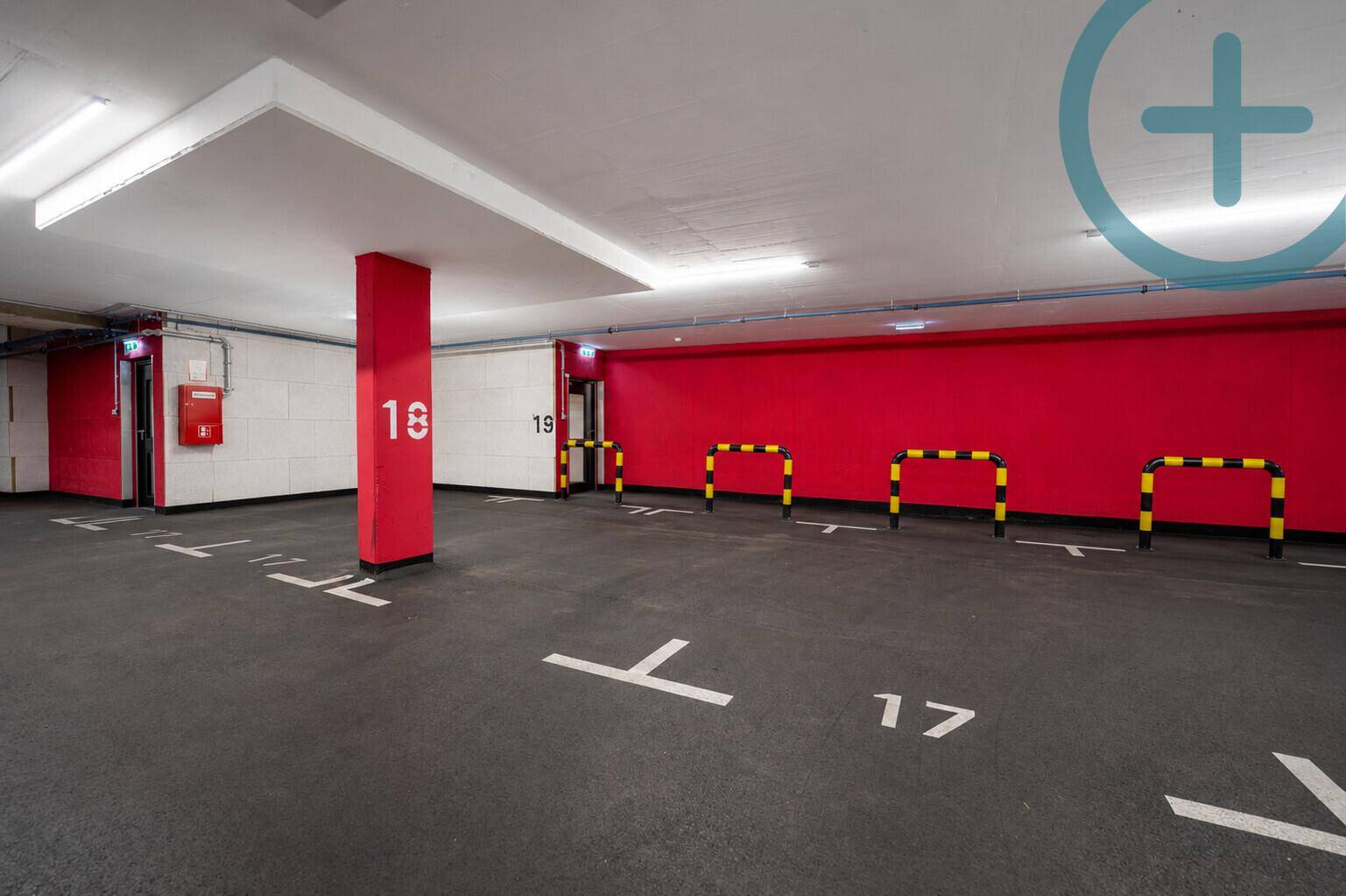 Geräumige Tiefgarage mit individuellen Parkplätzen und Sicherheitsausstattung an der Wand.