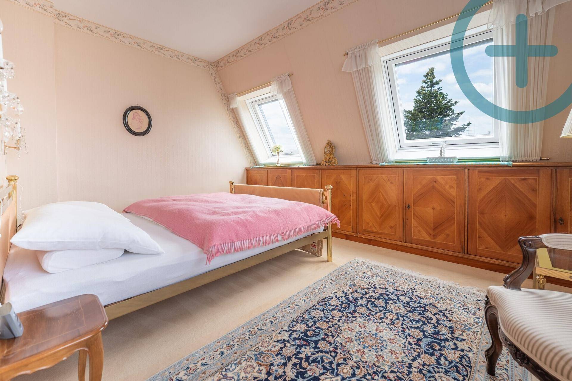 Helles Schlafzimmer im Dachgeschoss mit Bett, Einbauschränken und Dachfenstern.