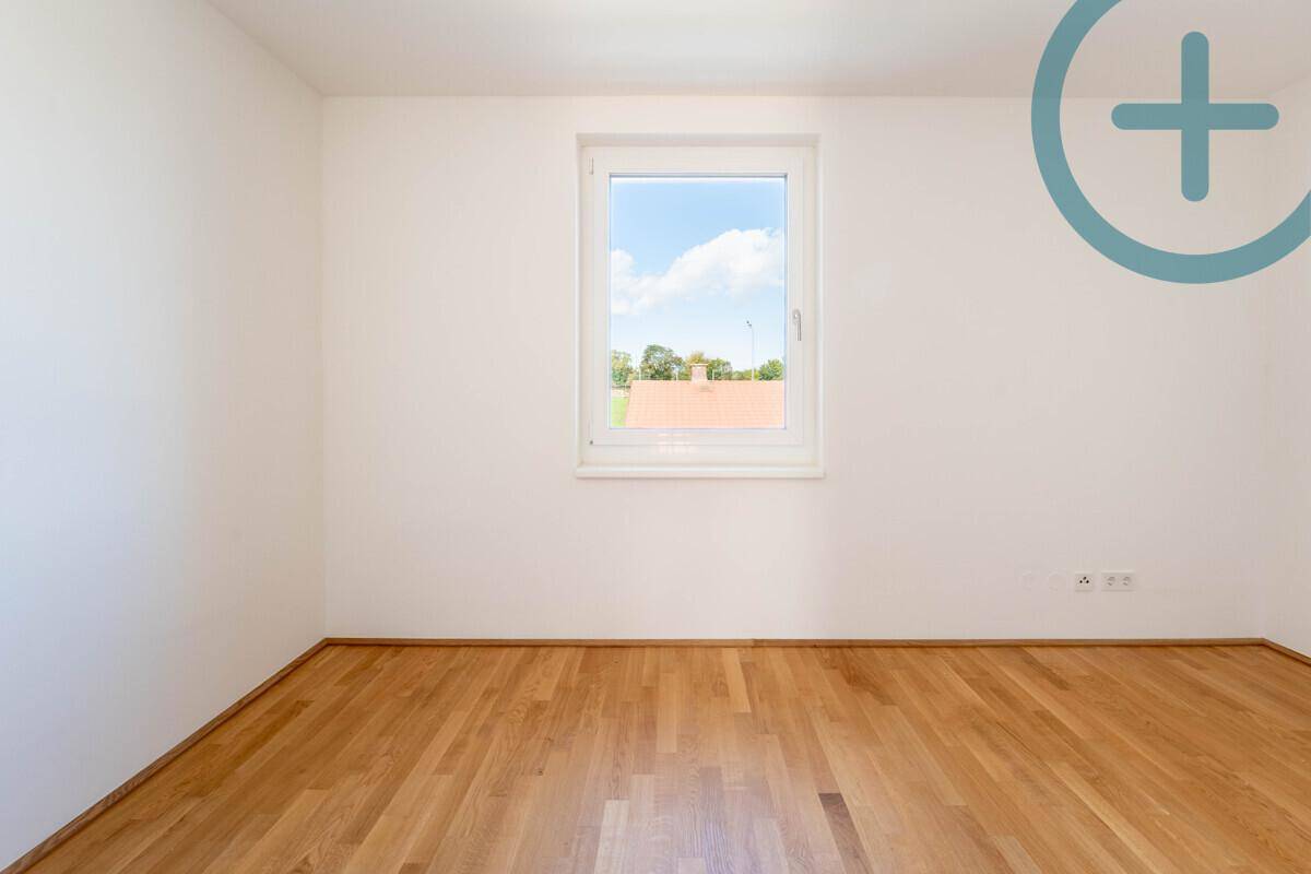 Geräumiges Schlafzimmer mit Parkettboden und einem großen Fenster, das viel Licht spendet.