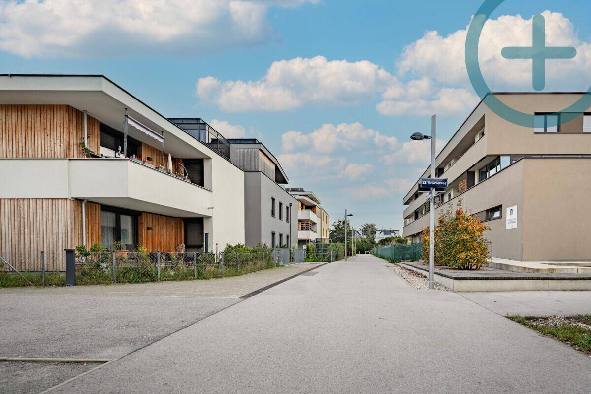 Moderne Wohnsiedlung mit zeitgenössischen Gebäuden und breiter Straße, umgeben von Grünflächen.