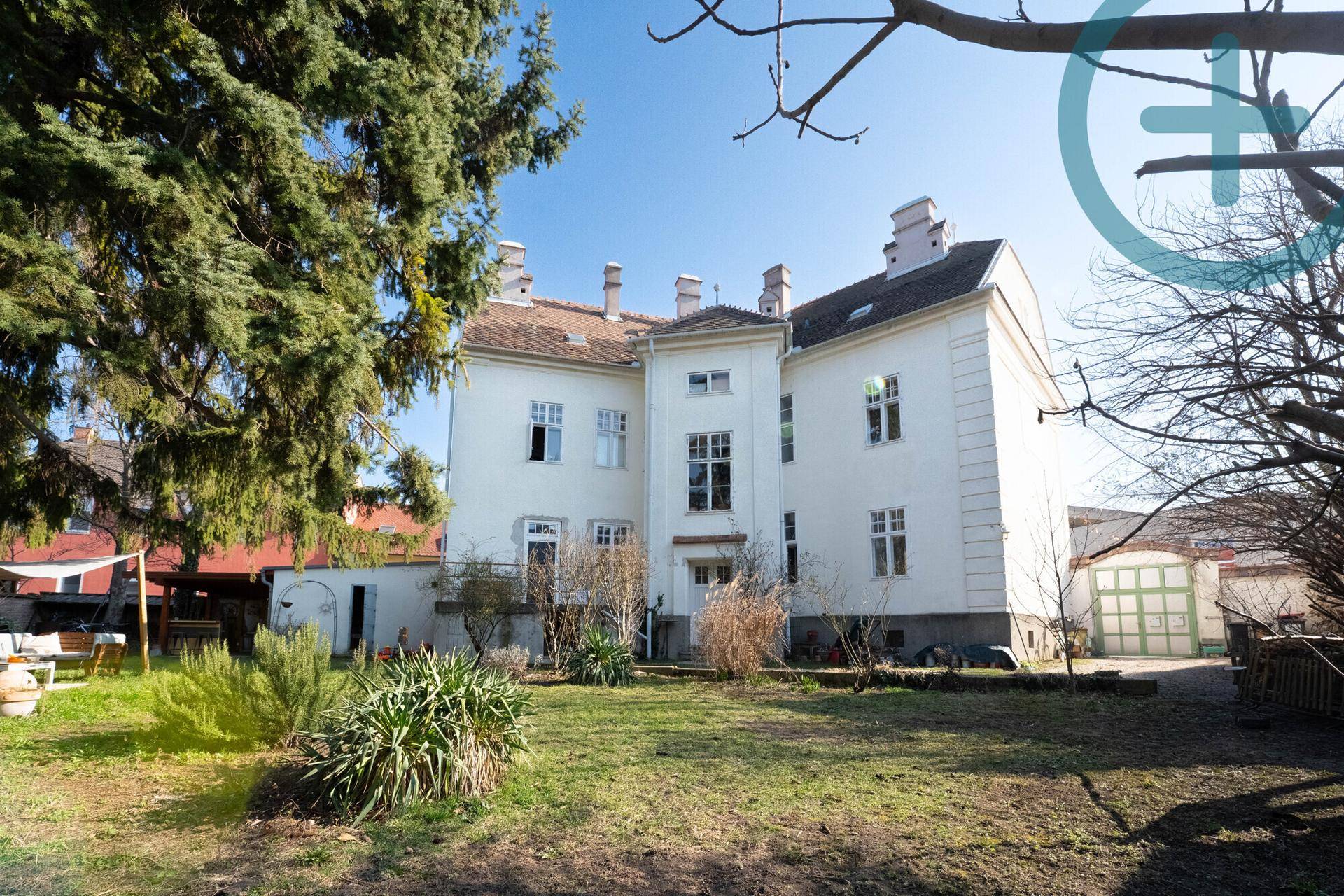 Großer Garten hinter dem historischen Gebäude mit viel Grünfläche und altem Baumbestand.