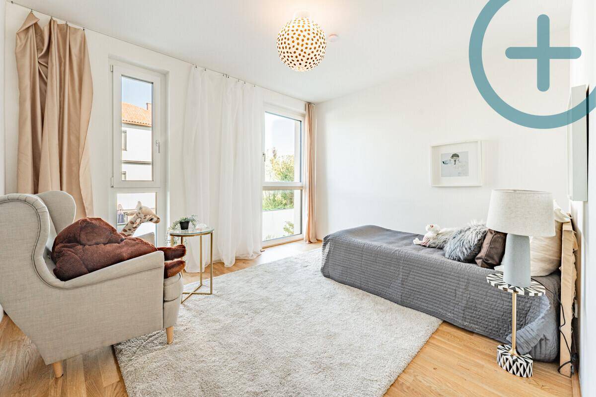 Helles Schlafzimmer mit Einzelbett, Sessel und großen Fenstern, ideal als Kinder- oder Gästezimmer.