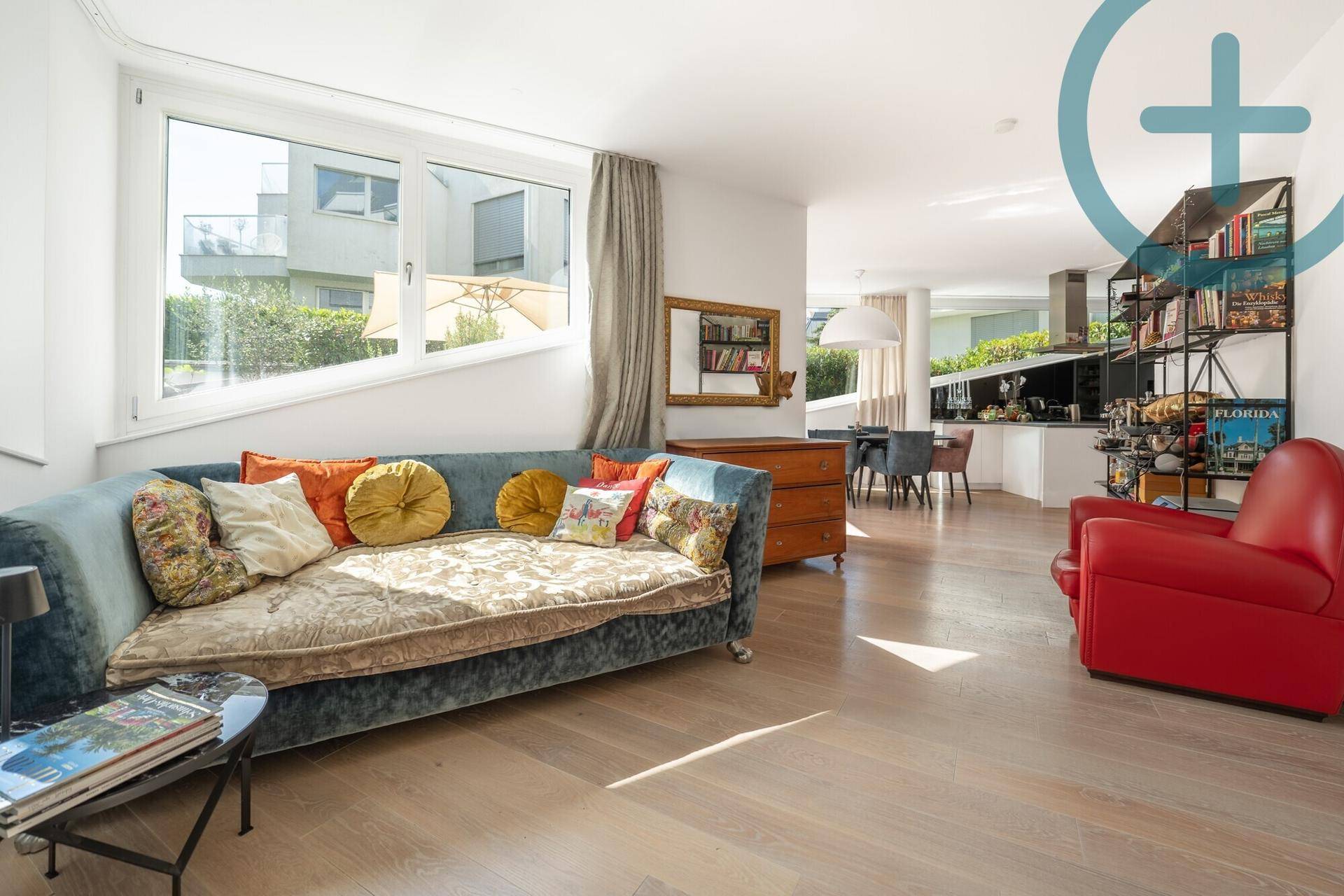 Helles Wohnzimmer mit Holzboden, bequemer Couch und Blick auf die umliegenden Gebäude.