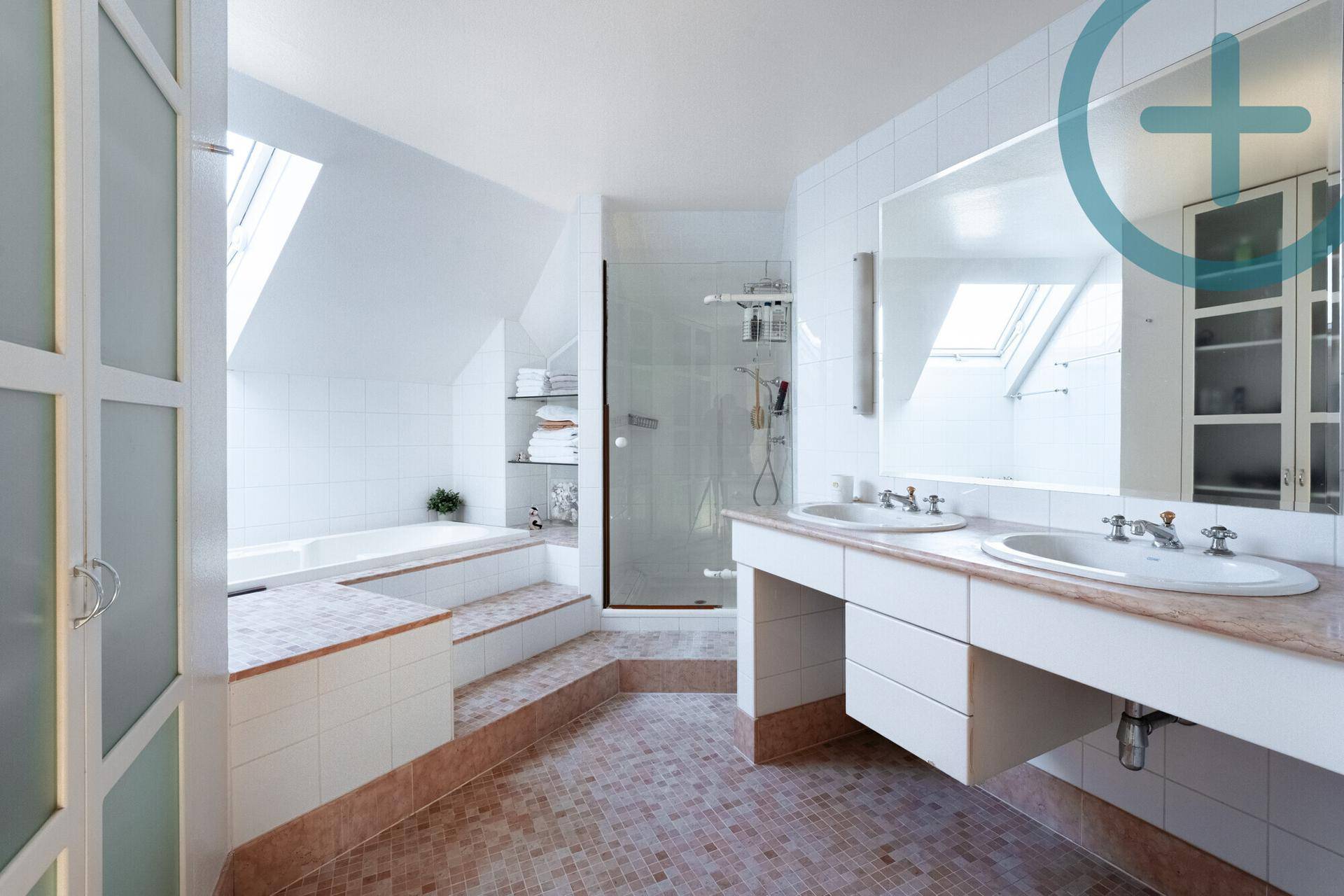 Großes Badezimmer mit Doppelwaschbecken, Badewanne und Dusche unter Dachfenstern.