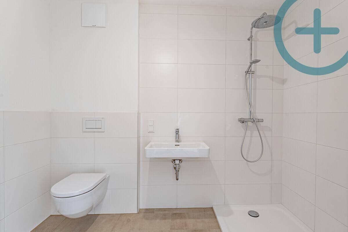 Modernes Badezimmer mit wandhängender Toilette, Waschbecken und einer ebenerdigen Dusche.