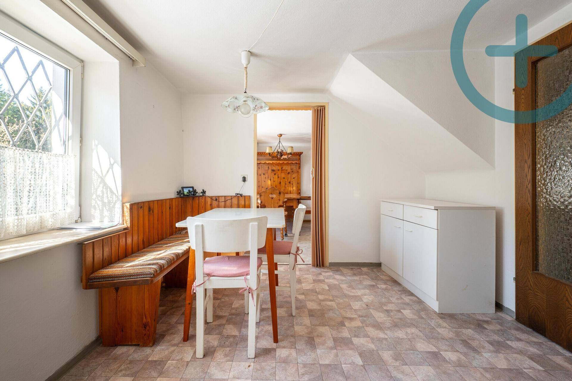 Gemütlicher Essbereich mit Holzbänken und einem Tisch, der zur Küche führt.