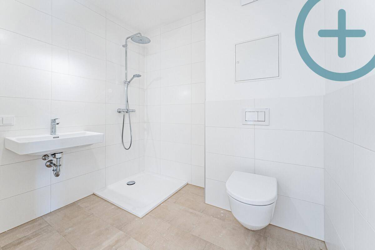 Modernes Badezimmer mit weißen Fliesen, ebenerdiger Dusche und wandhängendem WC.