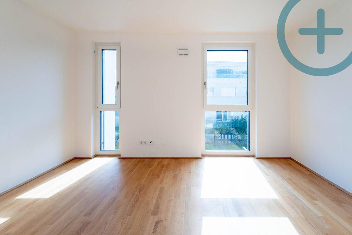 Lichtdurchflutetes Schlafzimmer mit Parkettboden und sonnigem Ausblick durch große Fenster.