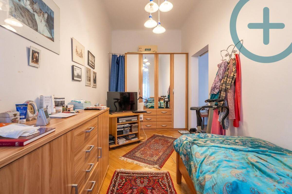 Funktionales Schlafzimmer mit Holzmöbeln, Spiegelschrank und Teppich auf Parkettboden.