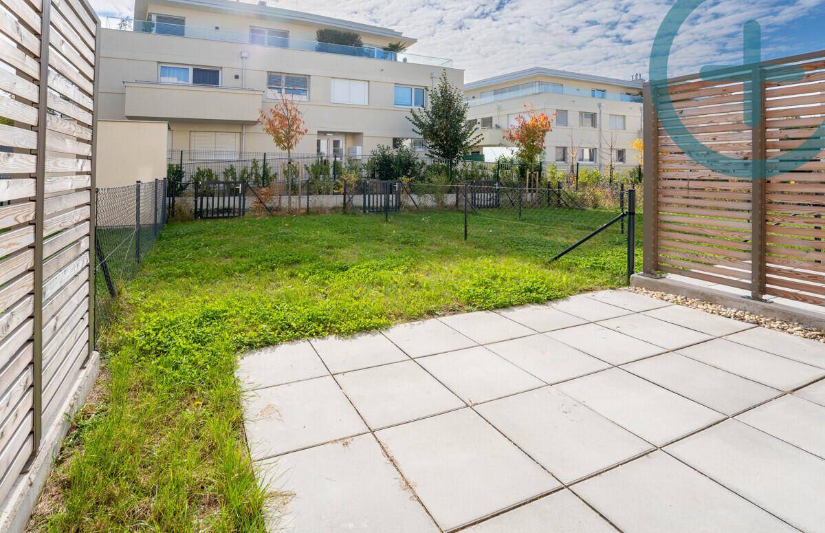 Privater Gartenbereich mit gepflasterter Terrasse und Holzabtrennung, umgeben von Grün.