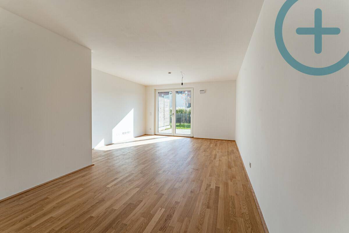Geräumiges, helles Wohnzimmer mit Holzboden und Schiebetür, die viel Tageslicht hereinlässt.