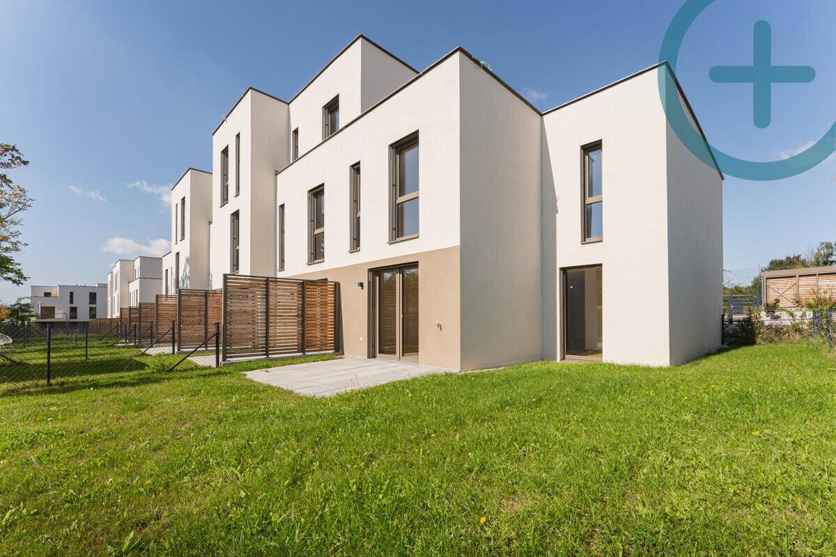 Moderne Reihenhäuser mit weißer Fassade, großen Fenstern und gepflegter Rasenfläche.