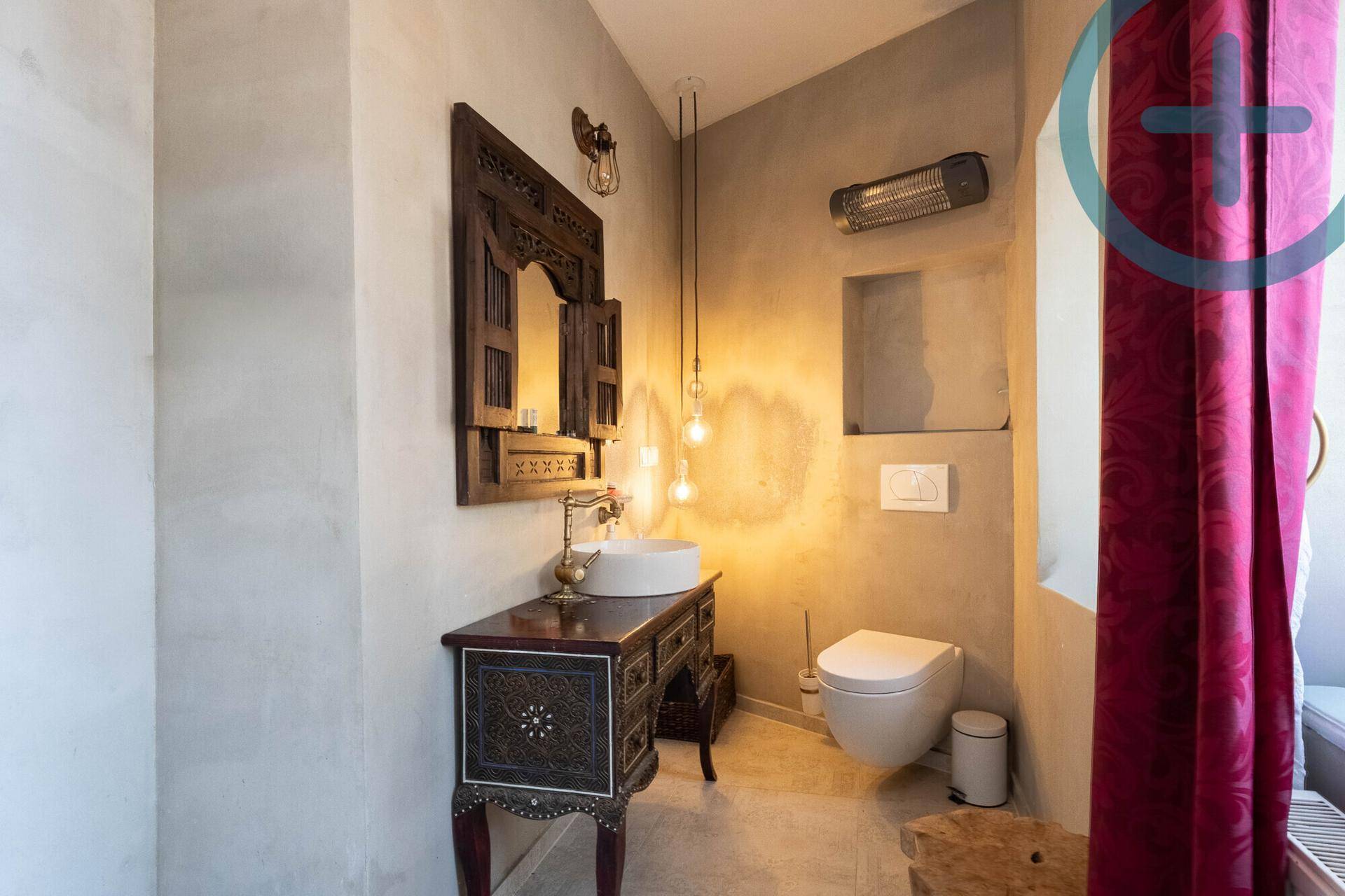 Stilvolles Badezimmer mit orientalischem Spiegel, Aufsatzwaschbecken und Wand-WC.