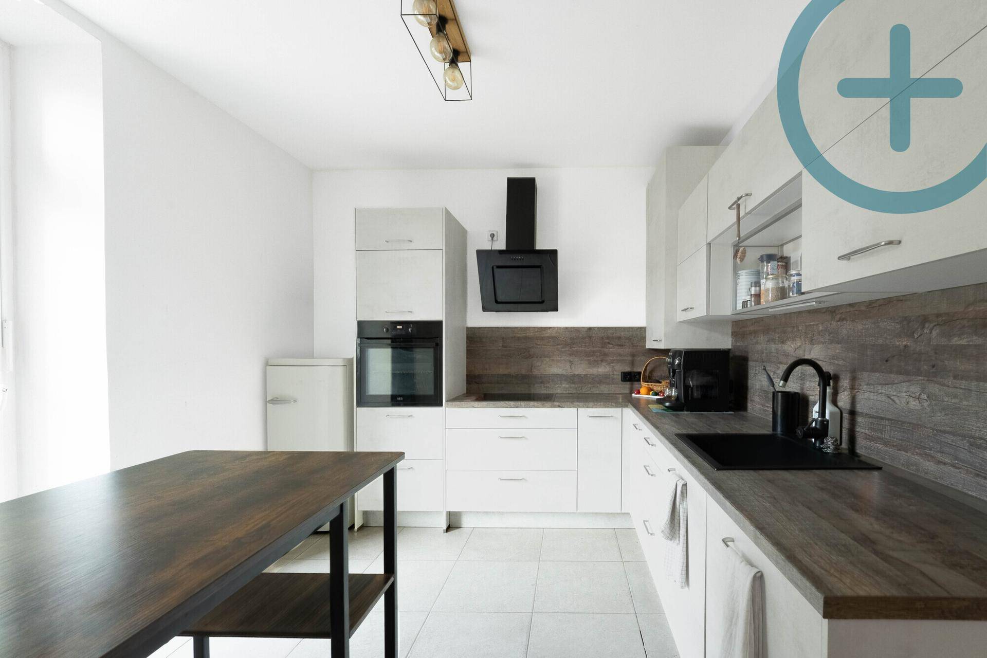 Moderne Küche mit weißen Schränken, dunkler Arbeitsplatte und integrierten Geräten.