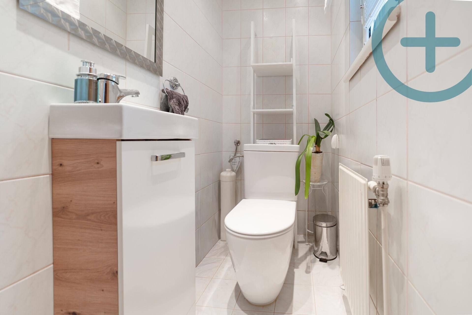 Kompaktes Gäste-WC mit modernem Waschtisch und Wand-WC in hellen Fliesen.