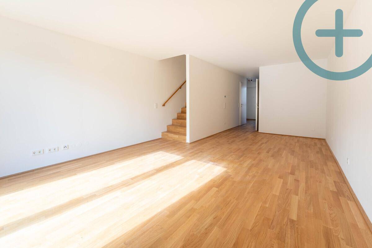 Geräumiger Wohnbereich mit Holzparkett und offener Treppe zu den oberen Etagen.