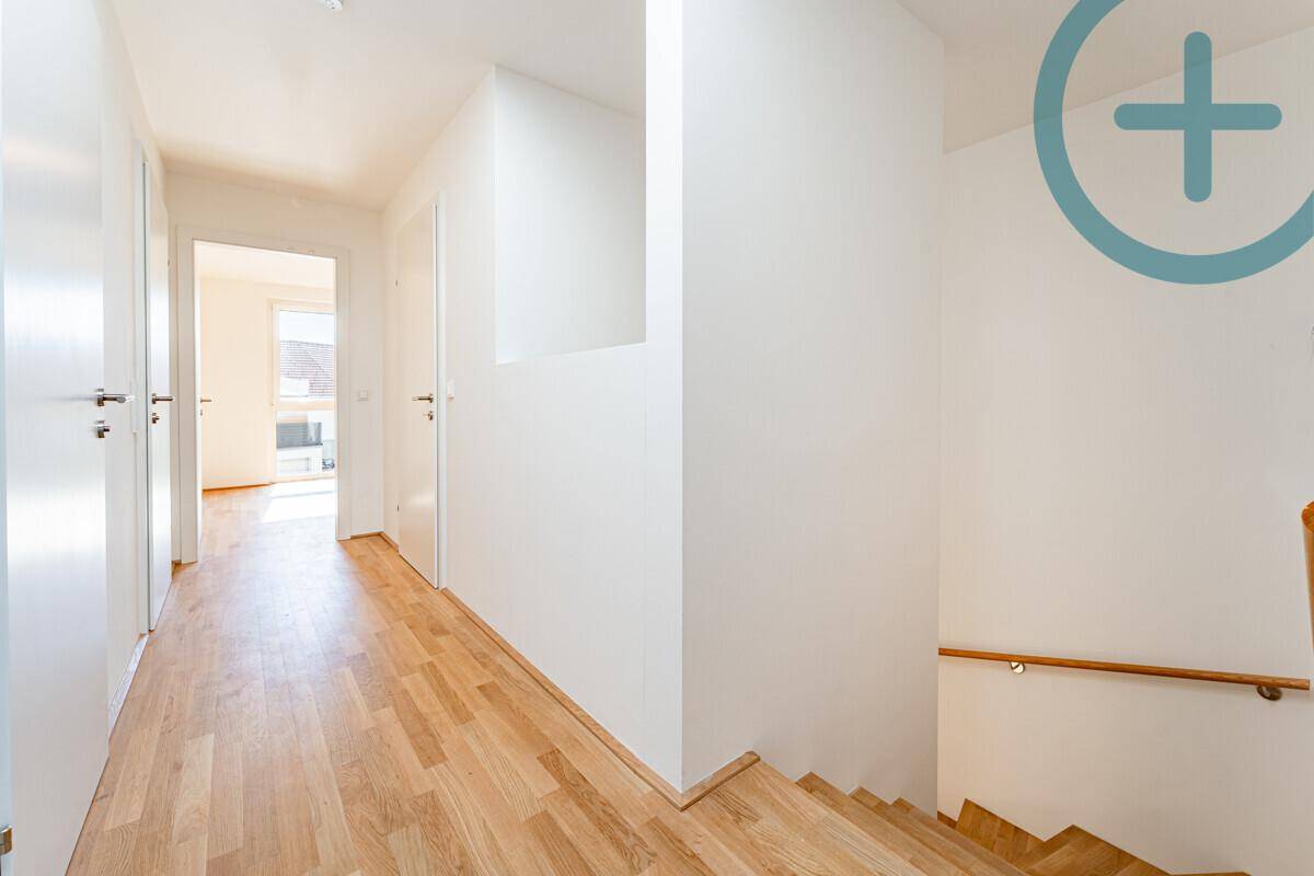 Heller Flur mit Parkettboden und Holztreppe, der die verschiedenen Ebenen des Hauses verbindet.