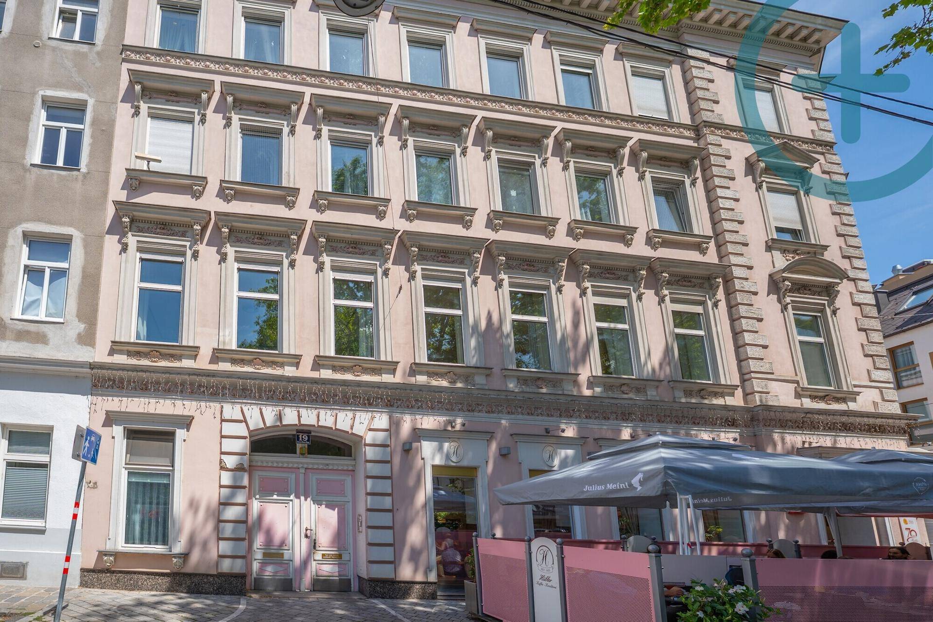 Historisches Gebäude mit rosa Fassade, vielen Fenstern und Außenbereich eines Cafés.