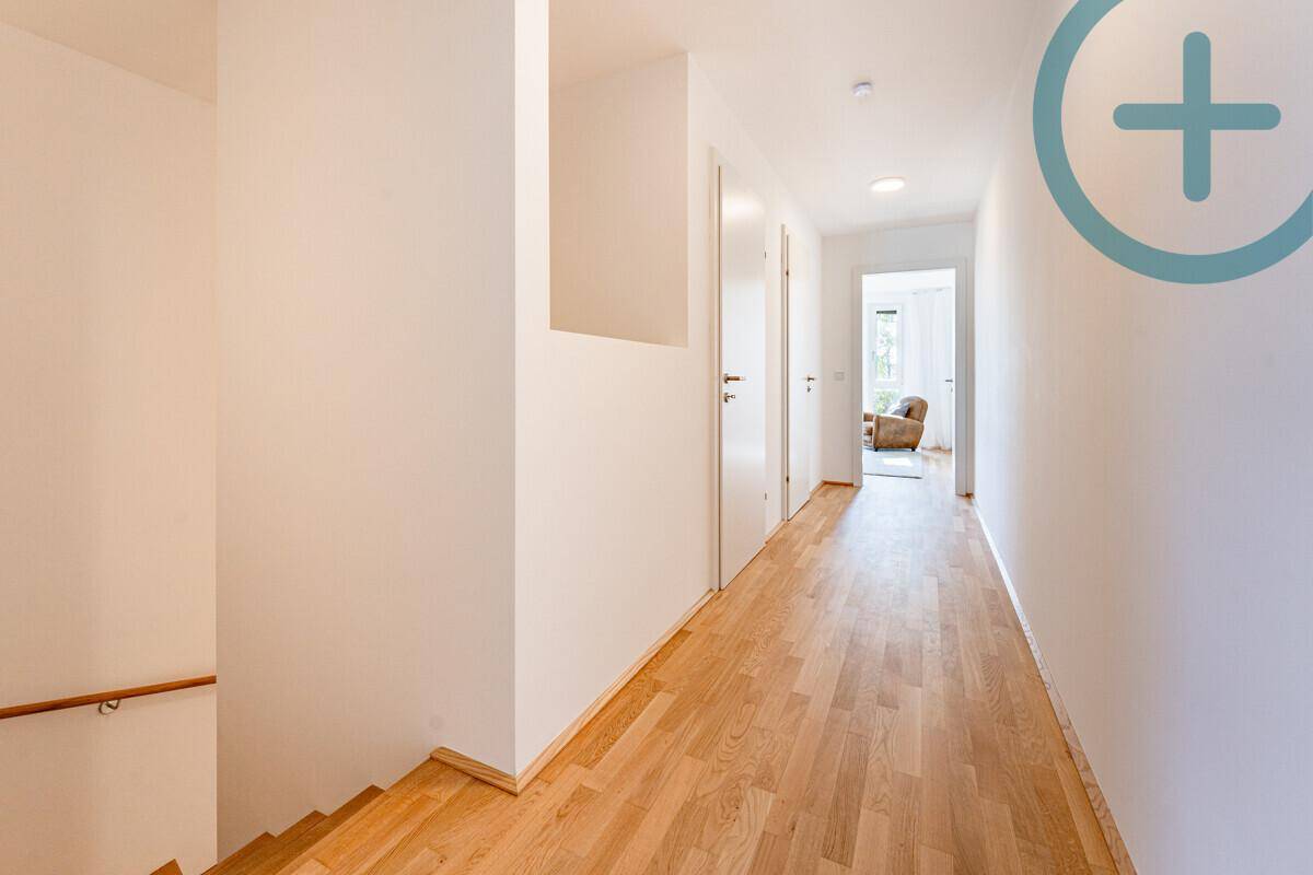 Langer, heller Flur mit Holzboden und Treppe, der zu weiteren Räumen führt.