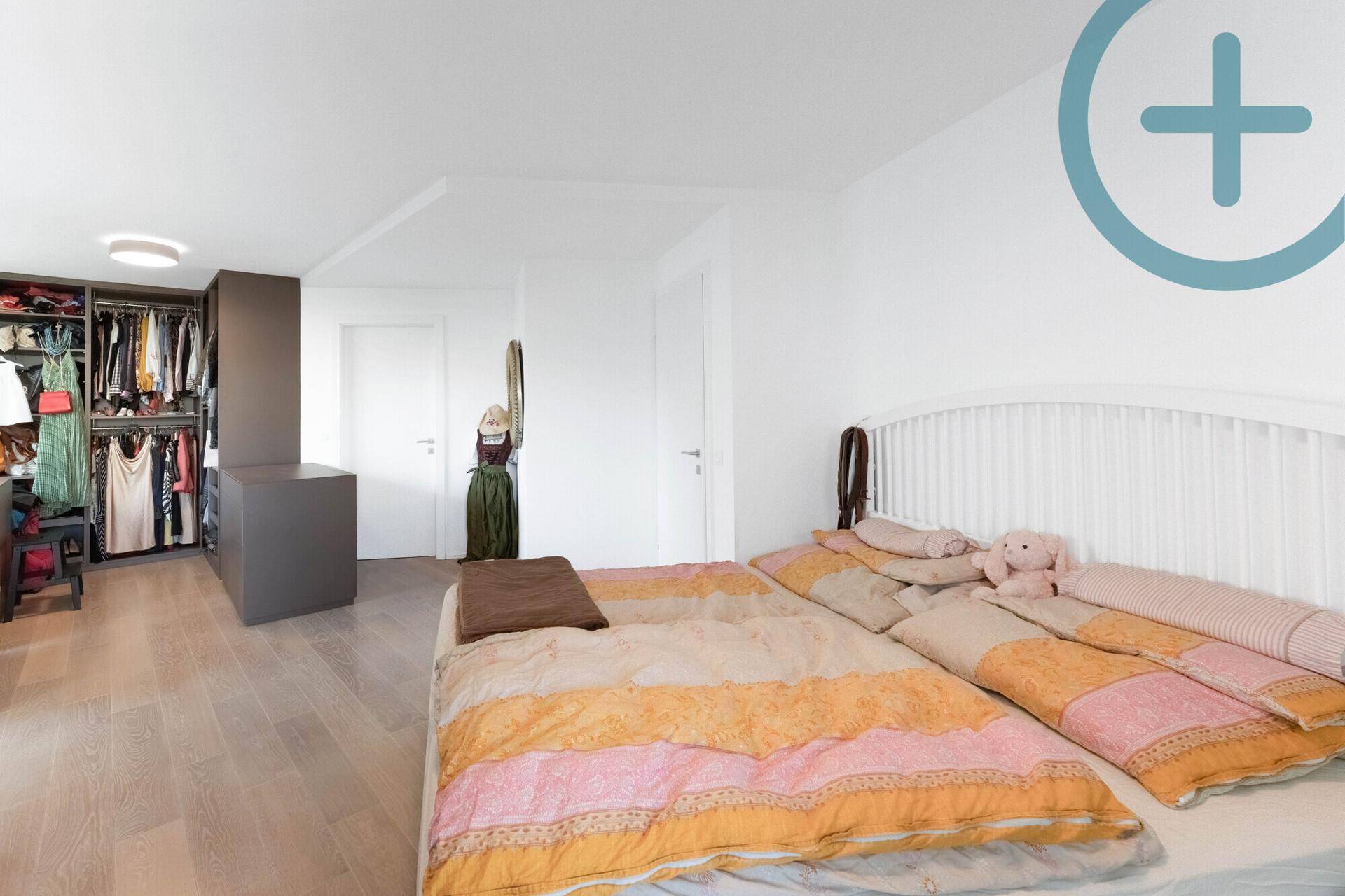Geräumiges Schlafzimmer mit Holzboden, Doppelbett und offenem Kleiderschrankbereich.