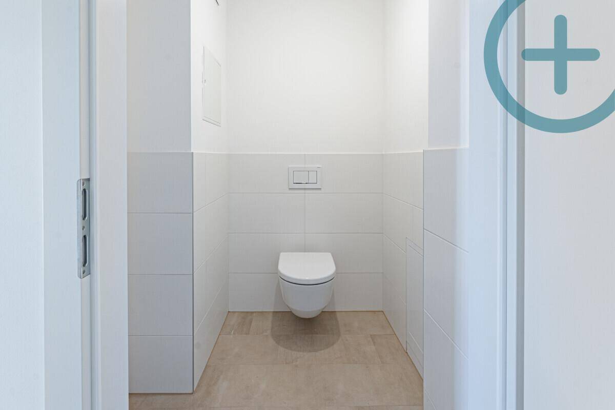Modernes Gäste-WC mit wandhängender Toilette und hellen Fliesen an Wänden und Boden.