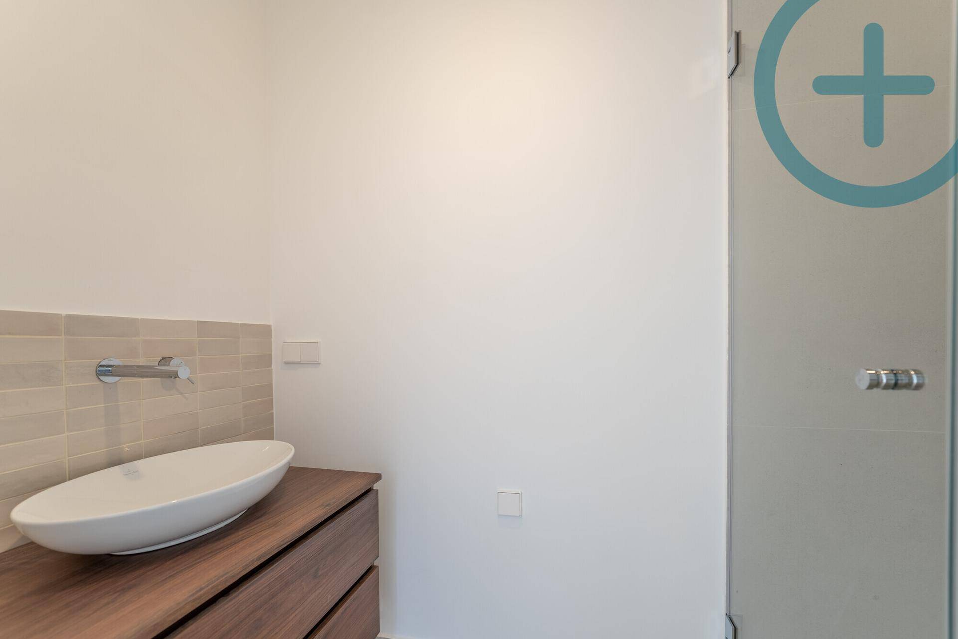 Modernes Badezimmer mit Aufsatzwaschbecken auf Holzunterschrank und Duschkabine.
