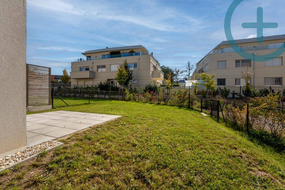Gepflegter Gartenbereich mit Terrasse und Blick auf weitere moderne Wohngebäude.
