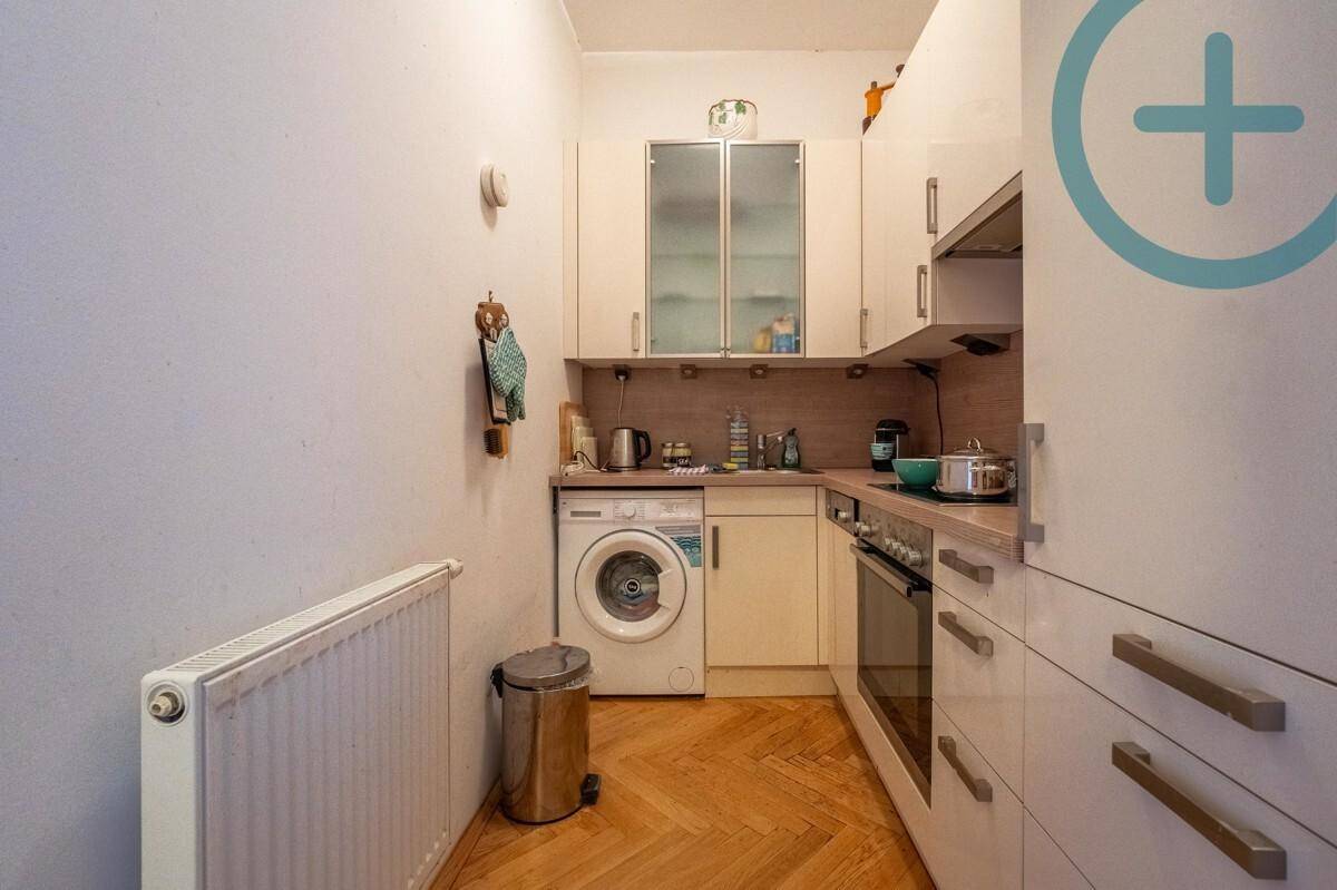 Kleine, funktionale Küche mit weißen Schränken, Waschmaschine und integriertem Backofen.