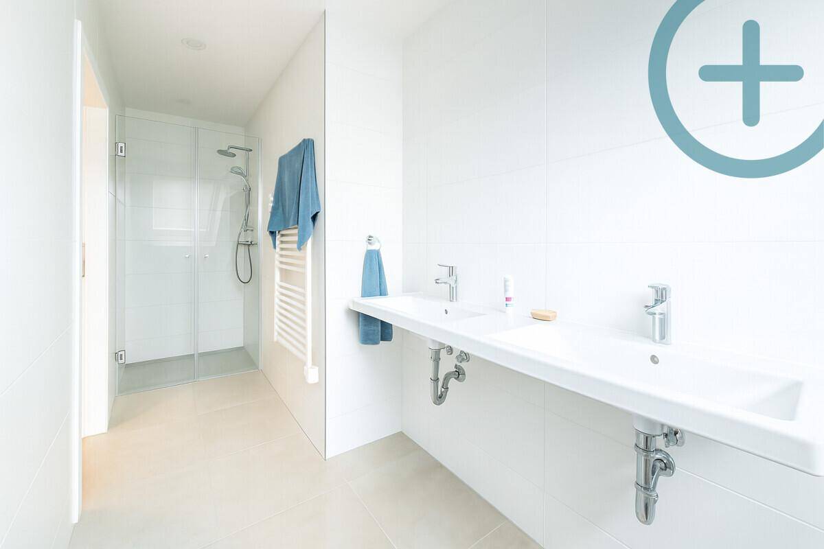Helles Badezimmer mit Doppelwaschbecken, begehbarer Dusche und beheiztem Handtuchhalter.