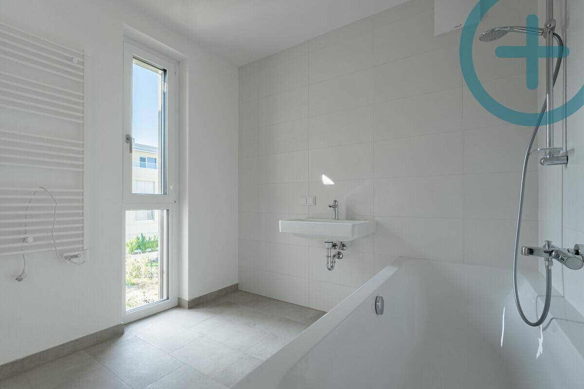 Modernes Badezimmer mit Badewanne, Waschbecken und Fenster, das viel Licht spendet.