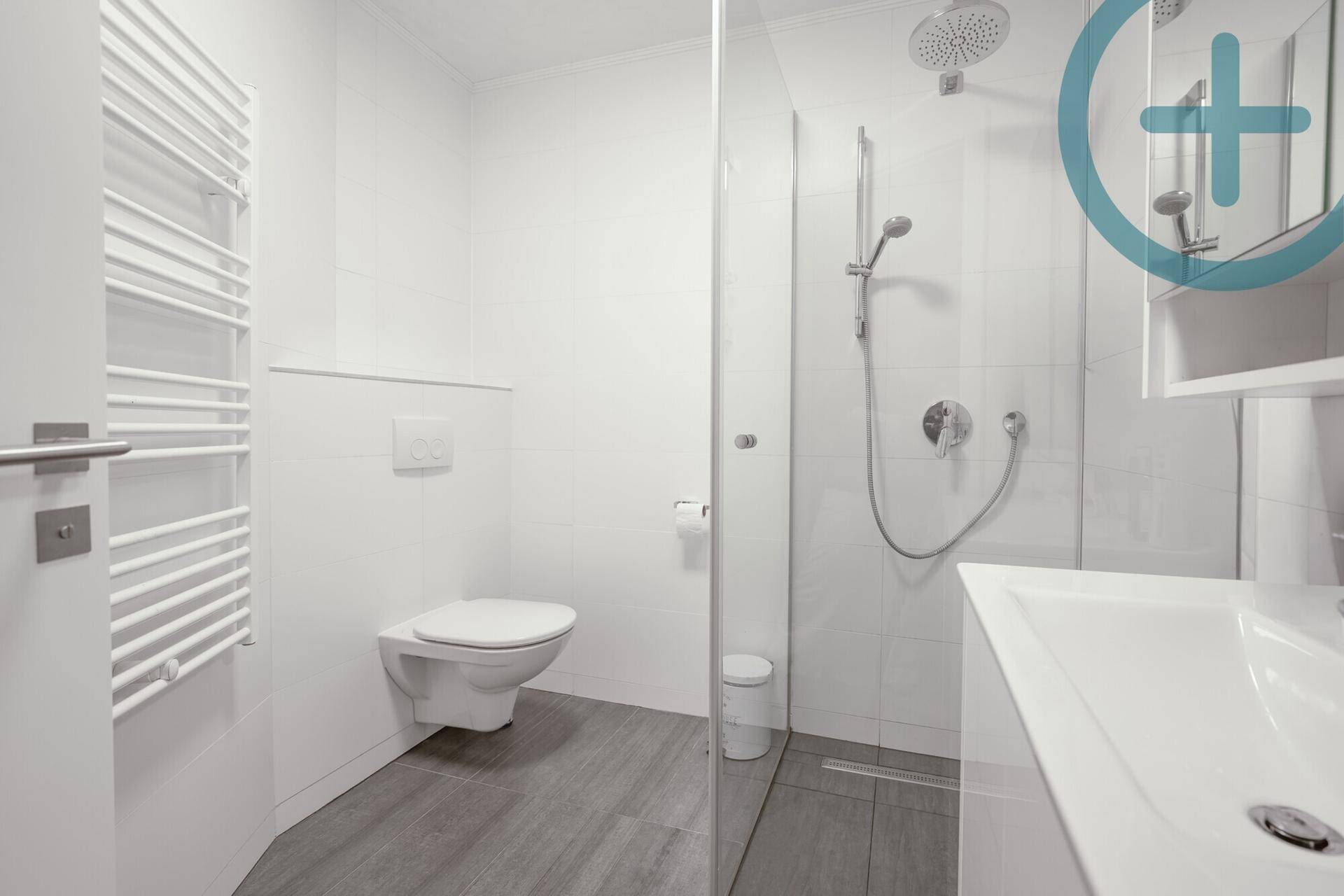Modernes Badezimmer mit ebenerdiger Dusche, wandhängendem WC und beheiztem Handtuchhalter.