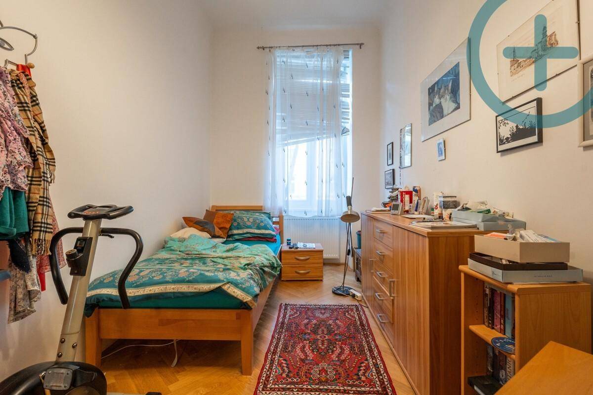 Schlichtes Schlafzimmer mit Einzelbett, Holzkommode und Fenster für natürliches Licht.