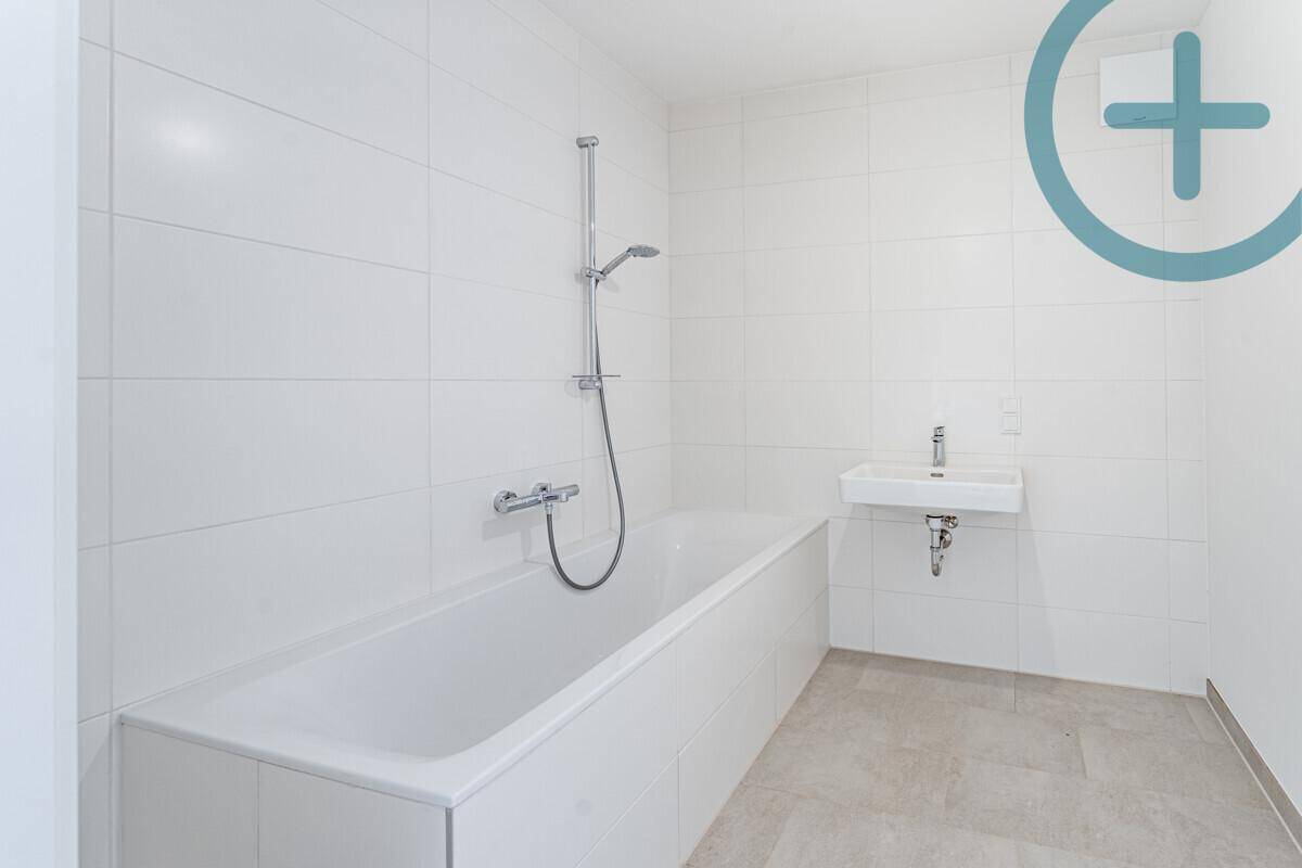 Modernes Badezimmer mit Badewanne, Waschbecken und weißen Fliesen an den Wänden.