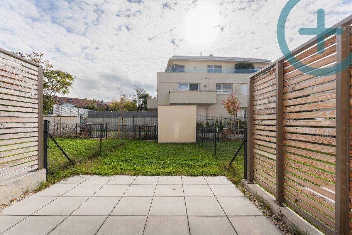 Kleiner privater Gartenbereich mit Terrasse und Rasenfläche, umgeben von Holzzäunen.