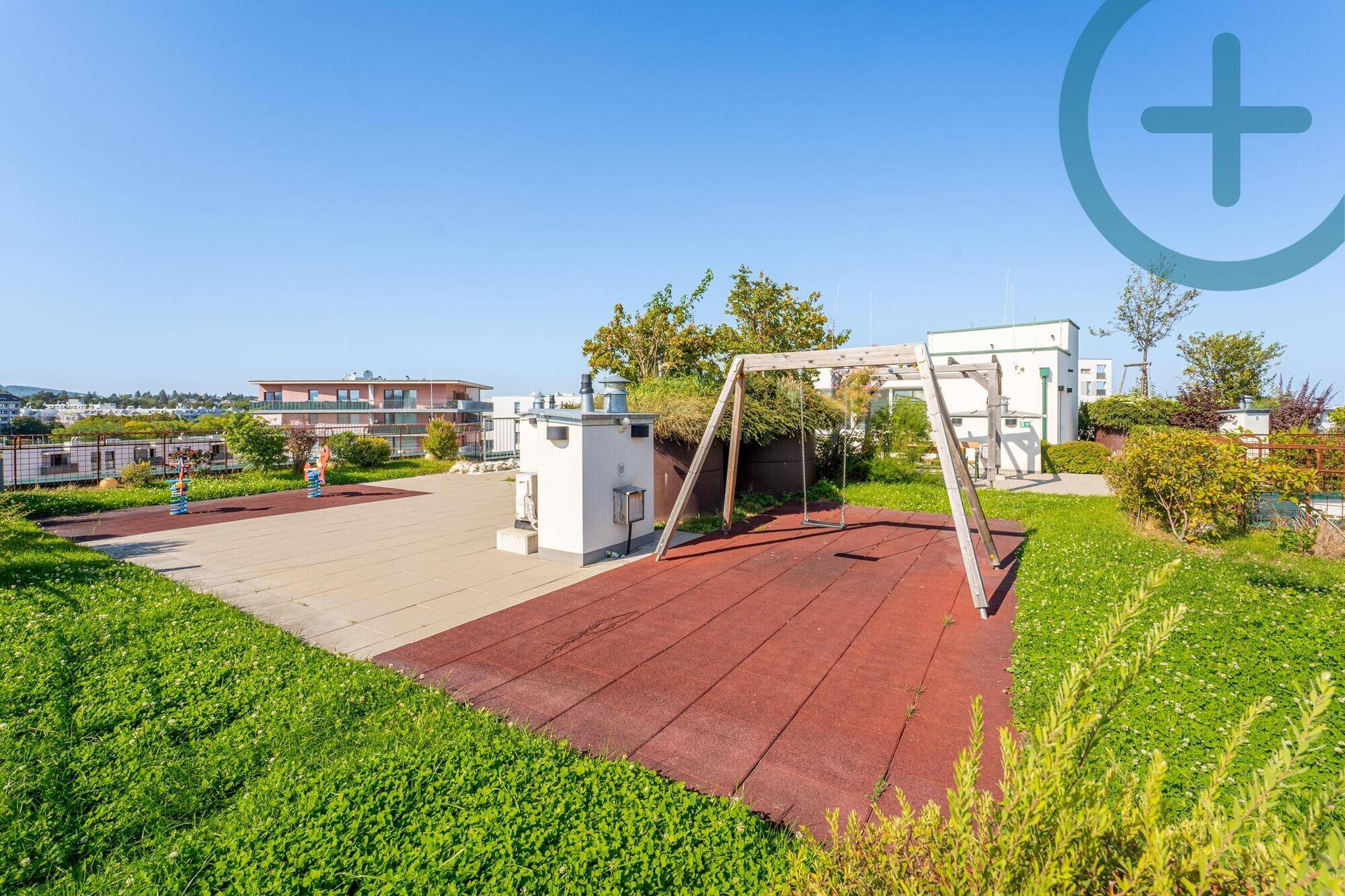 Dachterrasse mit Spielbereich, Schaukeln, Gummiboden und weiten Grünflächen.
