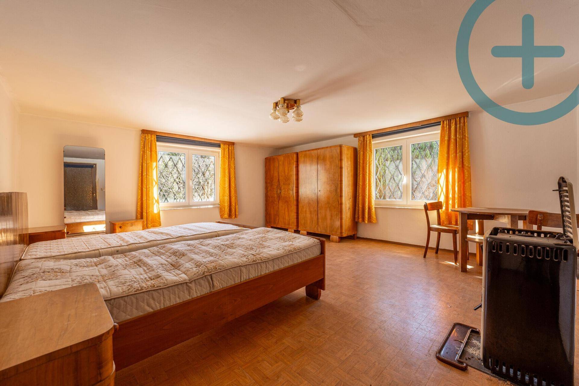 Geräumiges Schlafzimmer mit zwei Einzelbetten, Holzmöbeln und einem Ofen.