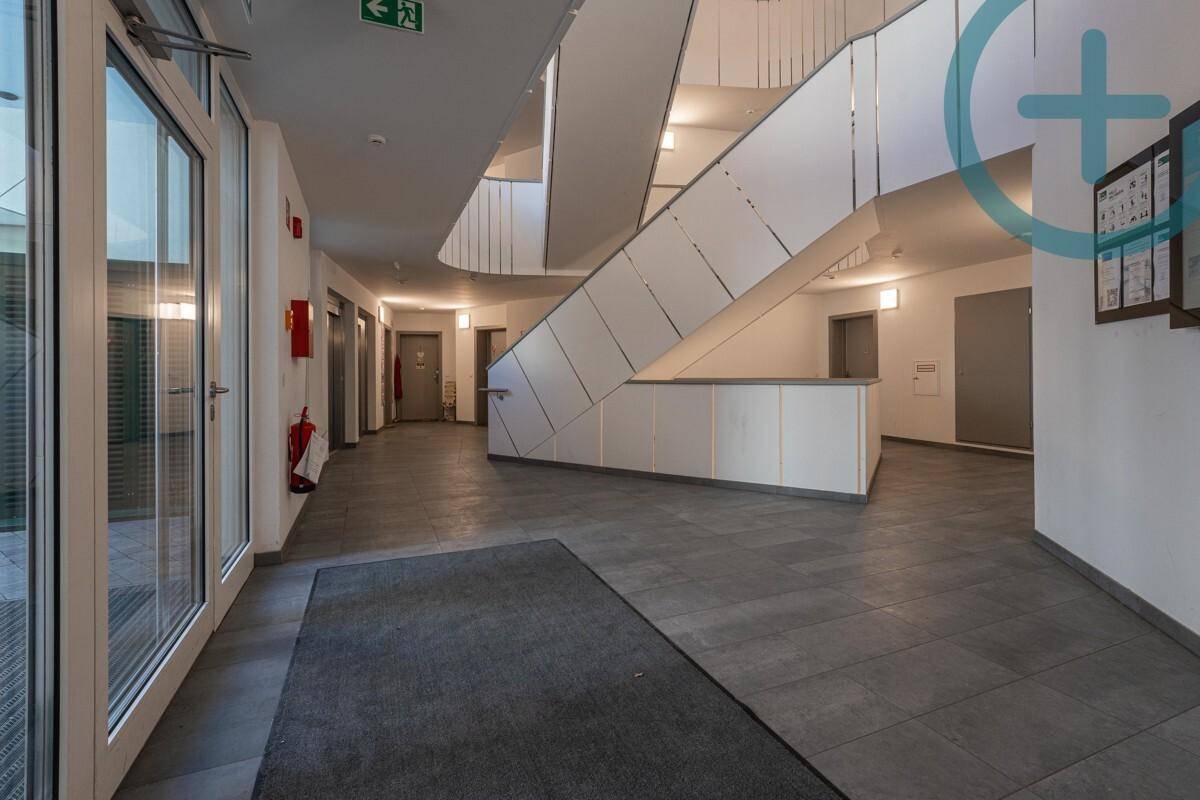 Moderner Eingangsbereich mit stilvoller Treppe, Fliesenboden und Zugang zu den Wohnungen.