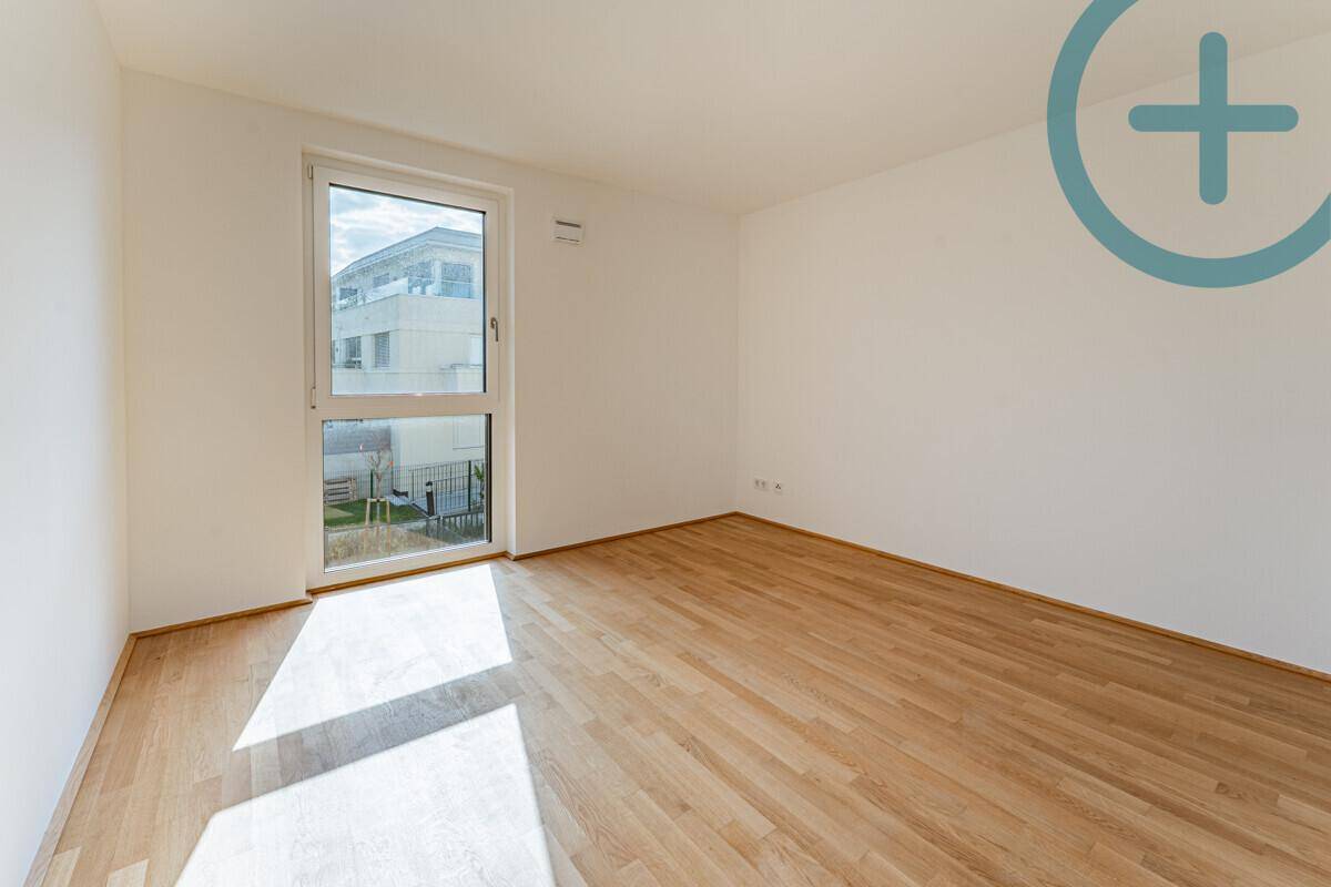 Sonniger Raum mit Parkettboden und großem Fenster, ideal als Schlaf- oder Arbeitszimmer.