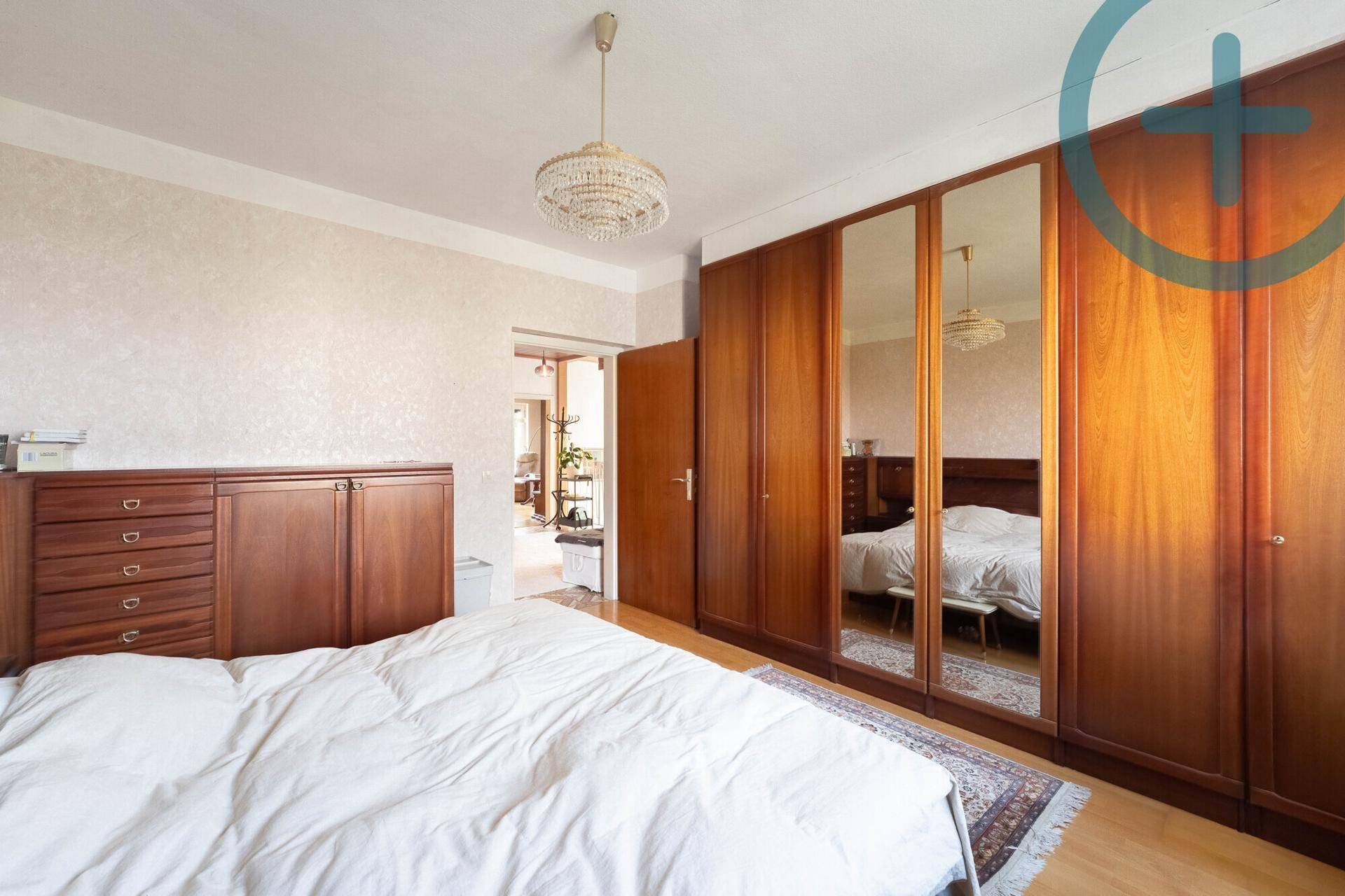 Schlafzimmer mit großem Einbauschrank, Spiegeltüren und Parkettboden.