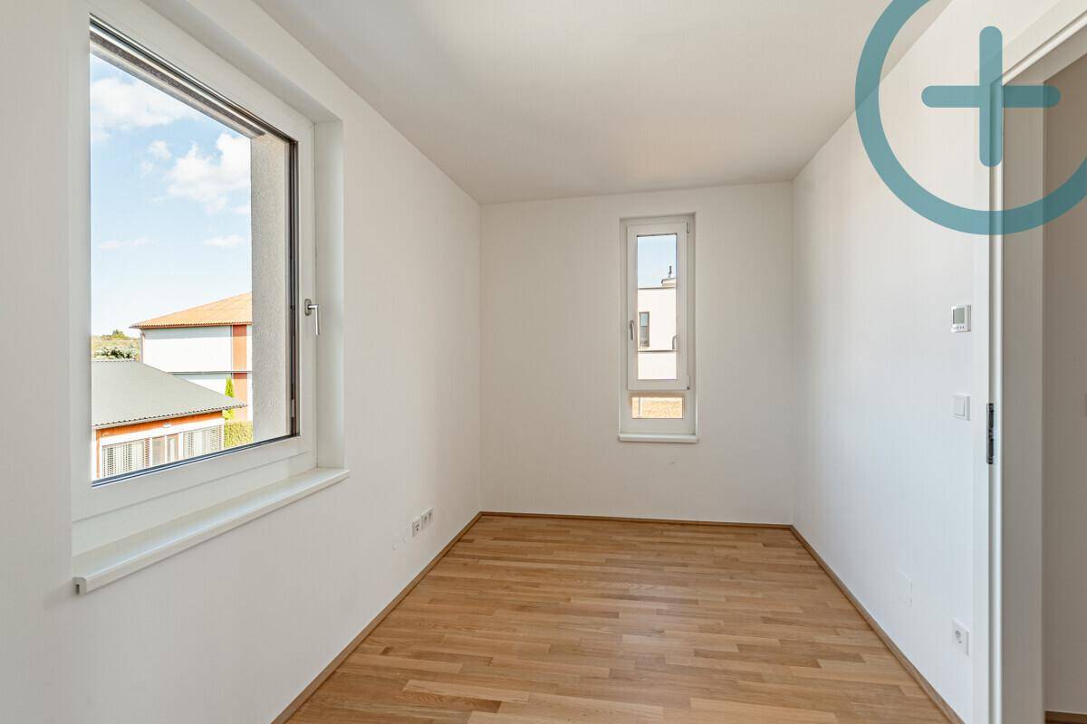 Helles Zimmer mit Parkettboden und zwei Fenstern, ideal als Kinder- oder Gästezimmer.