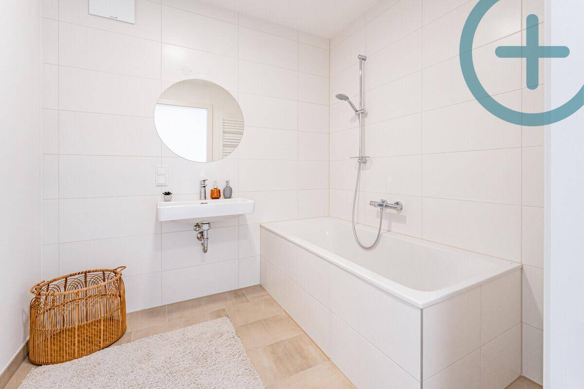 Modernes Badezimmer mit Badewanne, Einzelwaschbecken und beheiztem Handtuchhalter.