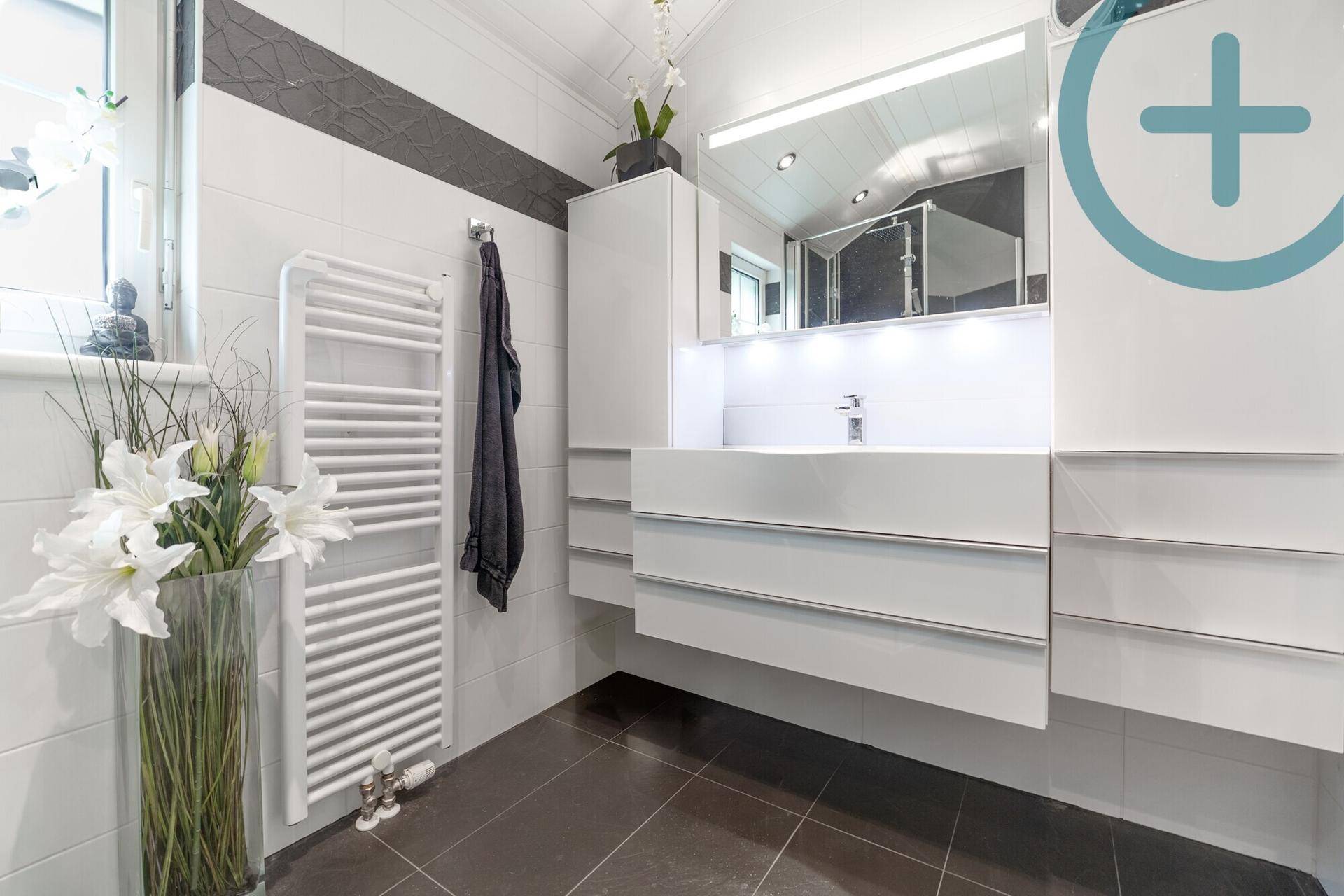 Modernes Badezimmer mit stilvollem Waschtisch, Spiegel und beheiztem Handtuchhalter.