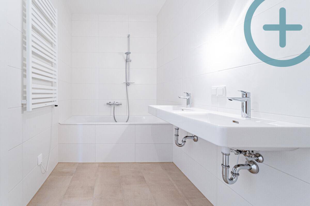 Modernes Badezimmer mit Doppelwaschbecken, Badewanne und beheiztem Handtuchhalter für Komfort.