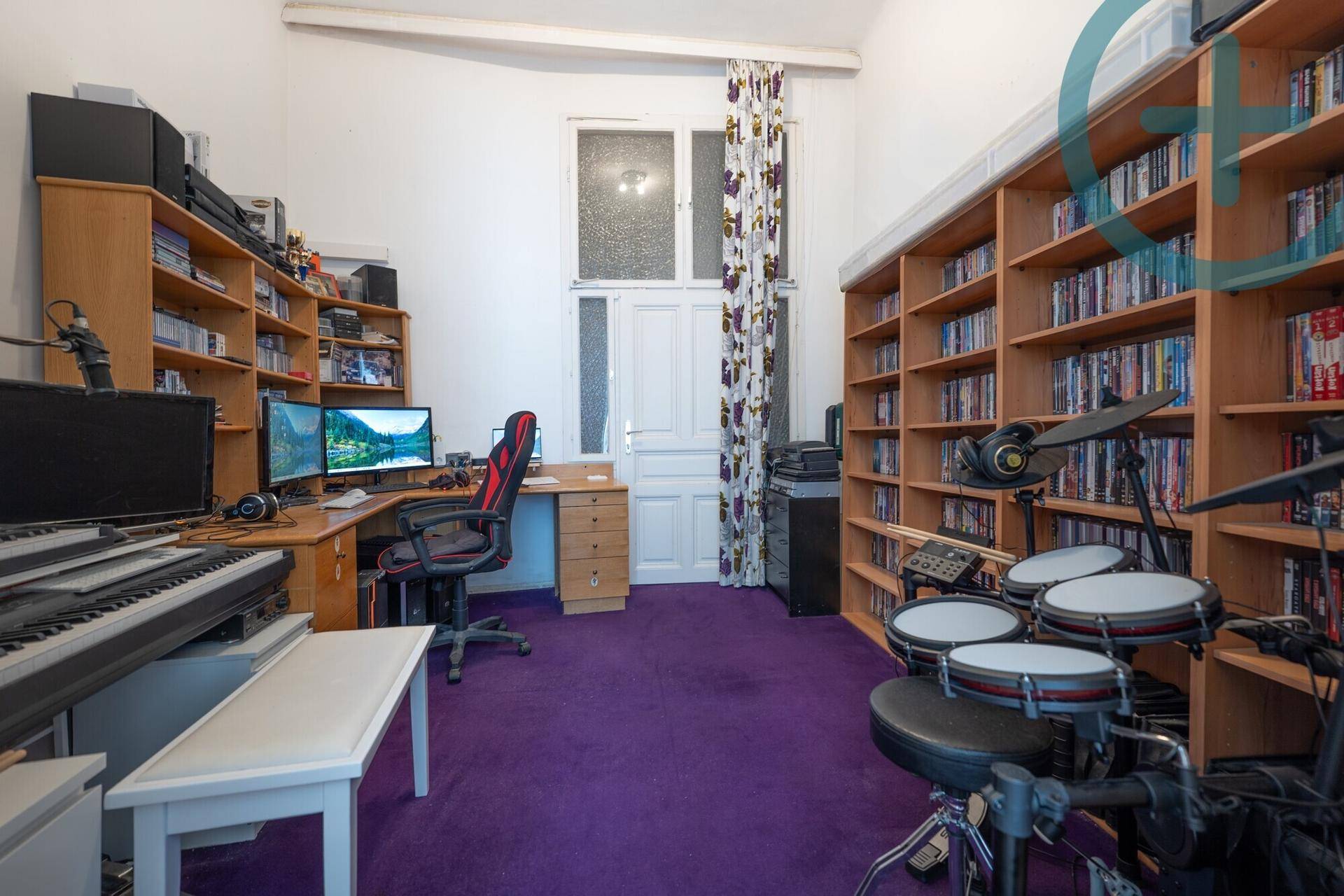 Medienzimmer mit lila Teppichboden, vielen Regalen und Musikinstrumenten.